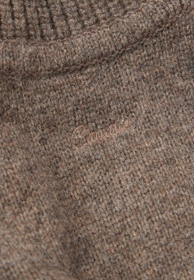 Pruunist kootud kangast tekstureeritud pind. Peen brändi logo on sisse pressitud heledamas varjus. Värvid sulanduvad loomulikult ühtlase välimuse saavutamiseks.
