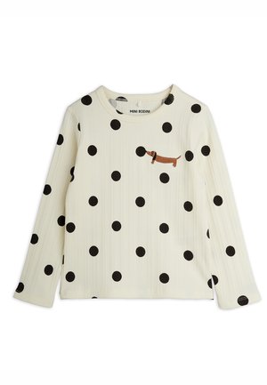 Cremefarbenes Langarmshirt mit schwarzen Punkten und einem kleinen braunen Dackel auf der Brust gestickt.