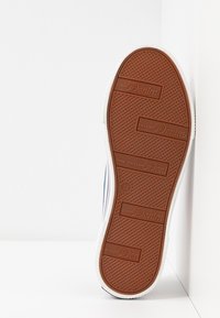 Semelle de basket blanche avec semelle en caoutchouc brun texturé, marque "Tom Tailor Denim", taille 37 visible au centre.