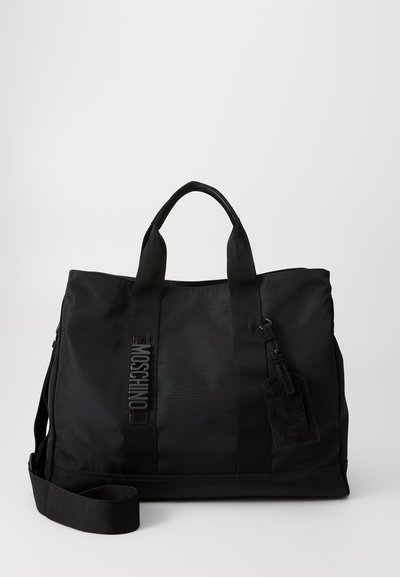 Musta nylon-tote laukku, jossa on kaksoiskannet, säädettävä olkahihna ja kohokuvioitu logodetalji. Sujuva rakenne ja tarrakiinnitys.