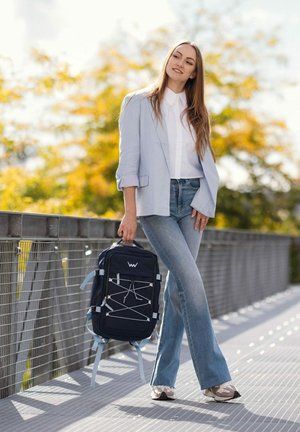 Tmavě modrý batoh s bílými akcenty, zipy a designem s bungee šňůrou. Kompaktní obdélníkový tvar s nastavitelnými popruhy.