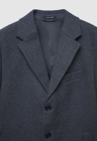 Cappotto in misto lana grigio con revers a punta, due bottoni frontali e una tasca sul petto. Fodera interna liscia, consistenza sottile.