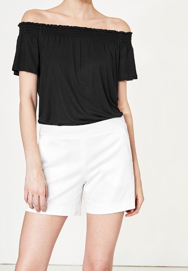 Haut noir à épaules dégagées avec encolure smockée, associé à un short blanc taille haute. Tissu lisse, coupe décontractée et design minimaliste.