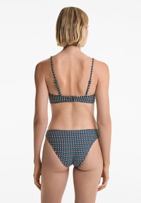 Bikini set s tmavým základem a geometrickým vzorem v tyrkysové, bílé a červené barvě. Nastavitelné popruhy a zapínání na klapku vzadu.