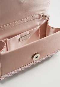 Pochette en satin rose pâle ouverte avec une poche, un fermoir magnétique en argent et une bordure inférieure ornée de perles en cristal.
