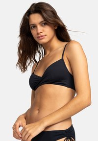 Černé bikiny s designem s propleteným předním dílem, tenkými nastavitelnými ramínky, hladkou strukturou a malou značkovou etiketou na boku.
