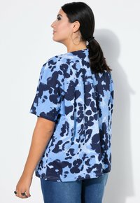Modrá a námořnická tričko s tie-dye vzorem, oversized střih, volný fit, krátké rukávy a kulatý výstřih. Materiál se zdá být měkký s texturovaným povrchem.
