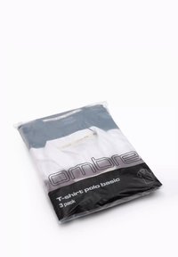 Trojbalení polo triček v plastovém sáčku, s modro-bílým designem. Balení zobrazuje název značky a popis produktu.