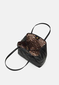 Borsa a tote nera trapuntata con un rivestimento a stampa leopardata. Presenta due manici e una chiusura a scatto. Nota gli accenti in metallo dorato.
