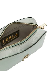 Pouch in vera pelle di un azzurro chiaro con una cerniera dorata, foderato all'interno con una texture morbida e con un'etichetta del marchio ben visibile all'interno.