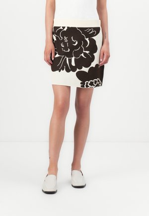 Jupe tricotée avec un motif floral noir sur fond crème, dotée d'une taille côtelée. La coupe est ajustée et arrive au genou.