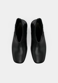 Černé kožené kotníkové boty s elegantním designem, špičatými špičkami, texturovanými akcenty na bocích a hladkým leštěným povrchem.