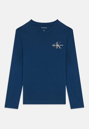 Ilgas rankovės tamsiai mėlynas marškinis iš minkštos medžiagos, su mažuoju metaliniu Calvin Klein Jeans logotipu ant krūtinės ir klasikine apvalia kaklo iškirpte.