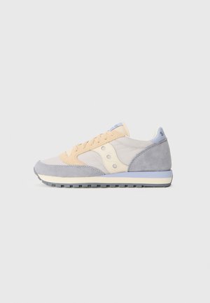 Niski sneaker w beżowym, jasnoszarym i kremowym kolorze z zamszowymi akcentami i teksturowaną gumową podeszwą, widoczny z boku na jednolitym tle.