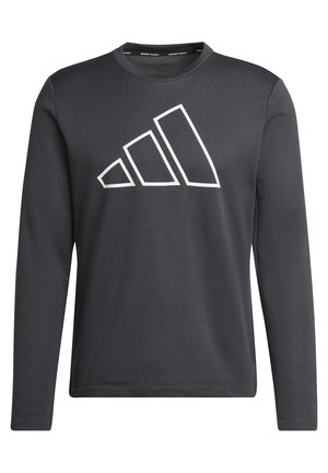 Homme portant un t-shirt à manches longues foncé avec un grand logo Adidas et un pantalon Adidas noir avec des bandes blanches.