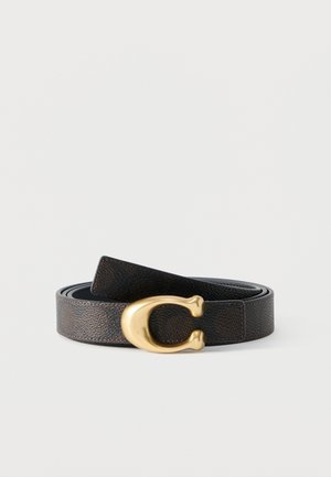 Tmavě hnědý kožený opasek s texturou, s velkou zlatou sponou ve tvaru písmene C, stočený na plocho na bílém pozadí.