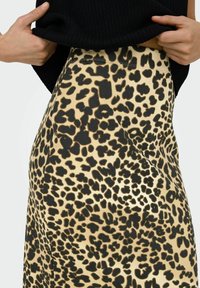 Beige en zwarte rok met luipaardprint, gemaakt van zachte stof. Heeft een hoge taille en een gladde textuur met een uitgesproken patroon.