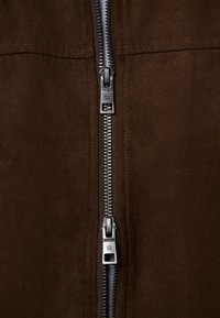 Brown suede jacket with a central metal zipper. The zipper features a silver tone and visible stitching along the edges.