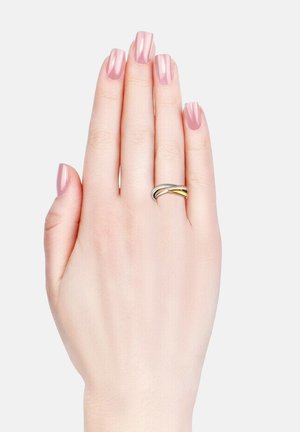 Silber- und goldfarbene, miteinander verwobene Ringe an einer Hand mit hellrosa lackierten Nägeln. Die Hand ist mit der Handfläche nach oben vor einem schlichten weißen Hintergrund positioniert.
