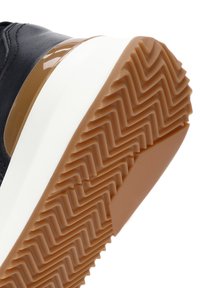 Zwarte schoen met een gladleren bovenkant. De rubberen zool heeft een diep zigzagpatroon in een lichtbruin en wit gelaagd ontwerp.