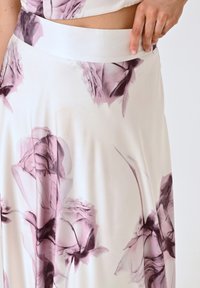 Maxi-jurk van een gladde, lichte stof met een witte achtergrond en grote, in aquarelstijl geschilderde paarse bloemetjespatronen. Elastische tailleband.