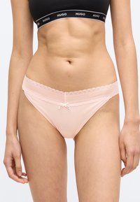 Chiloti roz deschis din bumbac, cu dantelă la talie, având un mic detaliu cu fundiță în partea din față și o textură moale.