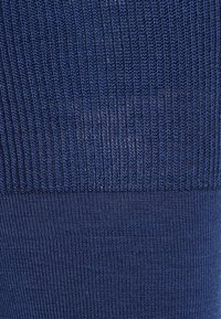 Tessuto a coste blu navy con trama testurizzata, caratterizzato da diversi modelli di punto e una sezione inferiore liscia. Materiale morbido e traspirante.