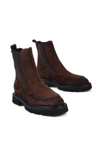 Brązowe zamszowe botki za kostkę z czarną gumową podeszwą, elastycznymi bocznymi panelami i przeszywaniami. Posiadają pętelkę na obcasie dla łatwego zakładania.