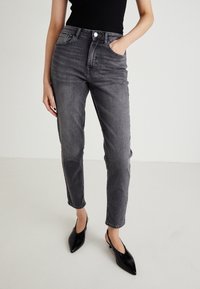 Mörkgrå högmidjade jeans med tapered ben, femficksdesign, silverfärgad knapp och lätt slitage vid låren.