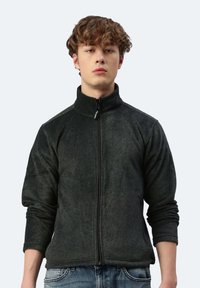 Schwarze Fleecejacke mit hohem Kragen, vollwertigem Reißverschluss und langen Ärmeln. Verfügt über eine leicht strukturierte Oberfläche und Seiten Taschen.