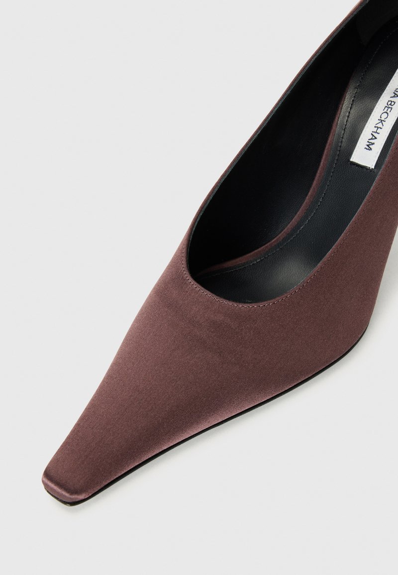 Spidse stiletter i mørk mauve satin. Har et udskåret design langs siderne, med en glat overflade og sort indvendig foring.
