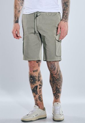 Khaki cargo shorts in a lightweight fabric, featuring side pockets, a drawstring waist, and a tailored fit. Worn with white sneakers.