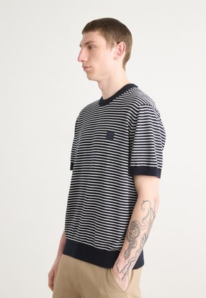 Gestreiftes, kurzes Strickshirt in Marineblau und Weiß, mit rundem Halsausschnitt und kleinen Brusttasche. Glatte Textur mit gerippten Abschlüssen.