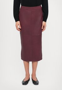 Jupe crayon en cuir bordeaux à finition texturée, longueur genou, avec une taille ajustée et des détails de couture subtils.