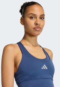 Sportovní tmavě modrý nátělník z texturované látky s přiléhavým střihem, ve středu s logem a širokými ramenními popruhy.