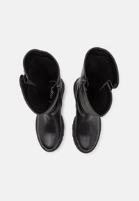 Botas de cuero negro hasta el tobillo con un acabado suave, punta redonda y cierres de cremallera a los lados; suelas de goma texturizadas para un mejor agarre.