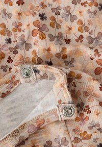 Kremowa tkanina z kwiatowym wzorem w odcieniach pomarańczu, brązu i szarości, z metalowym zatrzaskiem i fakturowanymi detalami szycia.