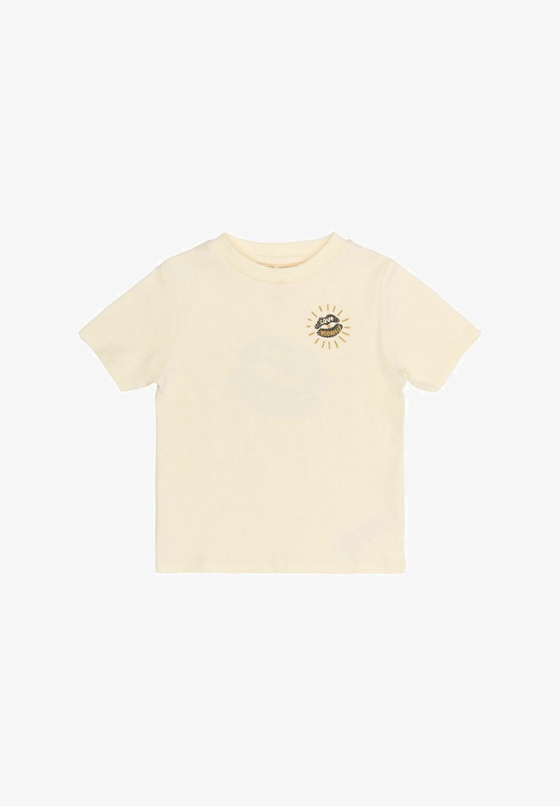 Camiseta de algodón en color crema claro con cuello redondo. Presenta un gráfico de labios en negrita impreso rodeado de rayos en negro y dorado. Mangas cortas.