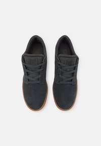 Dark gray suede sneakers with a low-top design, gray laces, and a brown rubber sole. Features a padded collar and logo on the tongue.