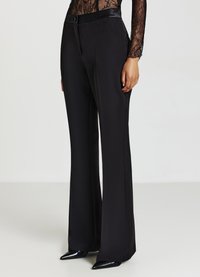 Schwarze maßgeschneiderte Hosen mit einem ausgestellten Bein Design, hergestellt aus glattem Stoff. Sie verfügen über einen flachen Bund und einen dezenten Verschluss vorne.