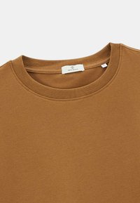 Sweatshirt marron à col ras du cou avec un col côtelé et une étiquette de marque blanche cousue à l'intérieur du col.