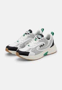 Vita och grå FILA-sneakers med svarta tåhattar, gröna detaljer, nätmaterial, tjocka vita sulor och dragflikar vid hälen.