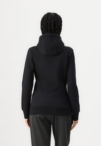Sweat-shirt à capuche noir avec des manches longues, des poignets et un ourlet côtelés. Texture lisse, design ajusté et sans logos ni motifs visibles.