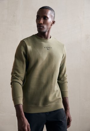 Olive green sweatshirt made of cotton blend, featuring a crew neck, ribbed cuffs, and "HYROX" logo. Smooth texture with minimal design.