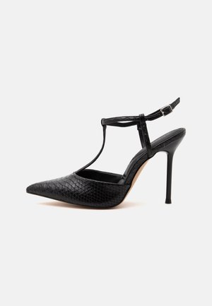 Scarpa nera con tacco alto, punta appuntita, motivo in pelle effetto coccodrillo, tacco sottile a spillo e cinturino alla caviglia con fibbia.