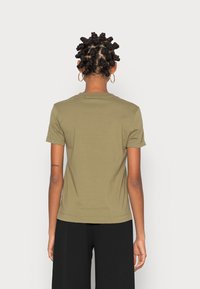 Olijfgroene t-shirt met korte mouwen en een ronde halslijn, gemaakt van zacht materiaal. Heeft een getailleerd ontwerp en een rechte zoom op de taille.