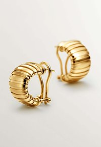 Pendientes de aro en tono dorado con un diseño acanalado y un acabado pulido, y un cierre articulado para un uso seguro.