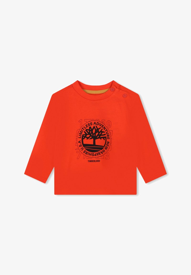 Chemise à manches longues orange en coton avec un graphisme d'arbre noir et le texte "Aventure Illimitée" ainsi que des boutons à l'épaule.