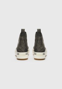 Baskets montantes avec un extérieur en toile gris foncé, surface texturée et semelle en caoutchouc blanc avec des rayures noires et un logo sur le talon.