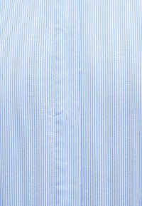 Υφασμα με κάθετες μπλε και άσπρες λεπτές ρίγες, με κεντρική ραφή και λεπτή ραφή σε λείο υφασμάτινο αποτέλεσμα.